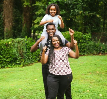 a man and two women holding a child on their shoulders